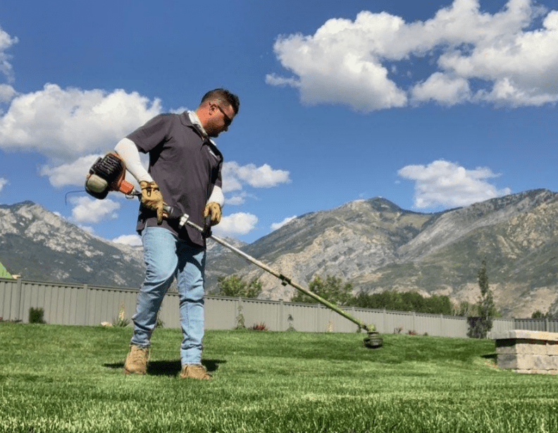 Millburn Lawn and Landscape Employee Trimming a local businesses lawn