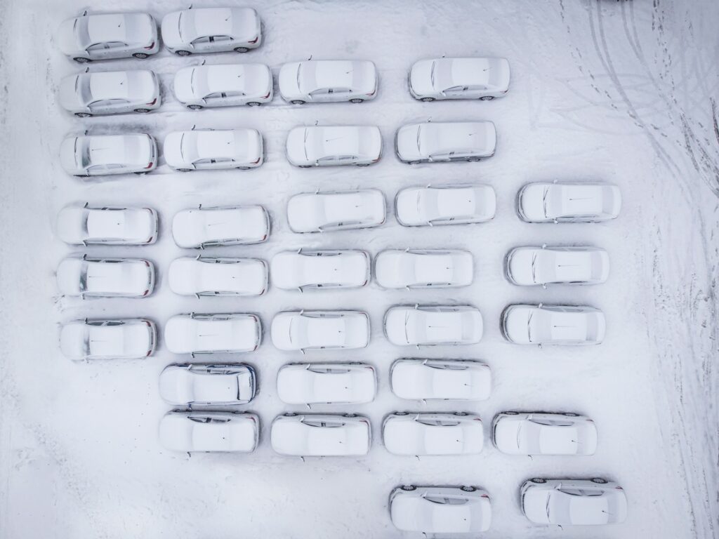 Aerial view of a city parking lot with many cars covered in fresh snow